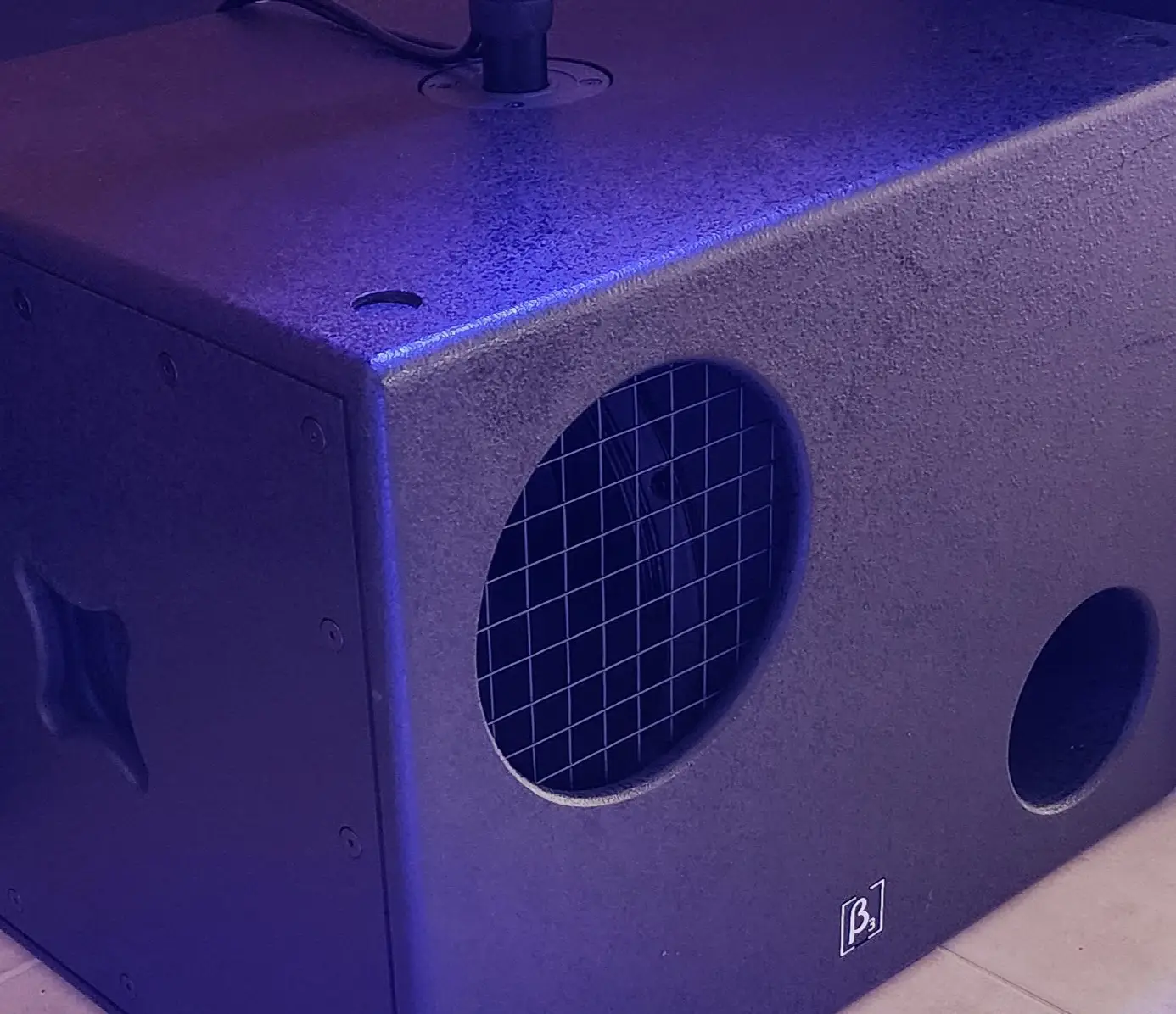 Subwoofer activo profesional Beta Three B3 de color negro con acabado texturizado y soporte para montaje en poste.